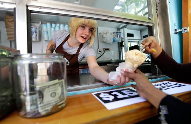 Caitlyn Faircloth, a worker with Molly Moon's Homemade Ice Cream, hands out free ice cream next to a tip jar, Monday, June 2, 2014, at a rally celebrating the passage of a $15 minimum wage measure outside Seattle City Hall in Seattle.