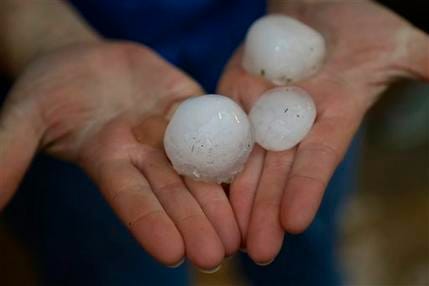 Mindy Rump holds golf ball-sized hail stone for a photographer following a severe thunderstorm in Blair, Neb., Tuesday, June 3, 2014. Severe weather packing large hail and heavy rain rolled into Nebraska and Iowa on Tuesday as potentially dangerous storms targeted a swath of the Midwest.