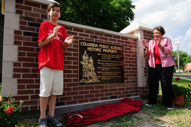 Jefferson Middle School seventh-grader Don Osborn, left, and Cindy Mustard unveil a historical marker Tuesday at the school. There has been a school at Eighth and Rogers streets in Columbia since 1881, and the marker celebrates that history.