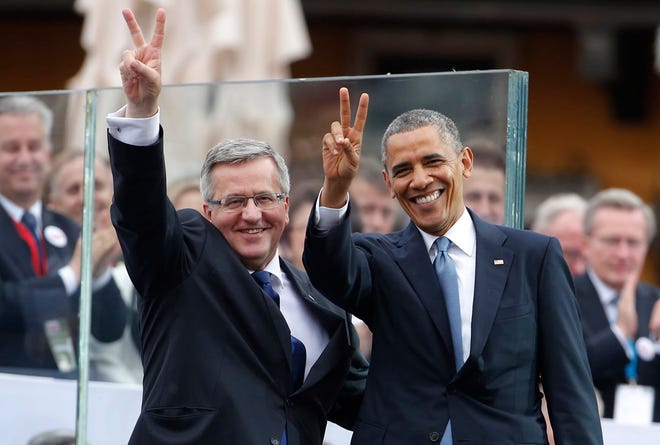 U.S. President Barack Obama, right, and Polish President Bronislaw Komorowski make the victory sign after Obama spoke at the 25th anniversary celebrations of Poland's first free elections led by the Solidarity movement at the Royal Square in Warsaw, Poland, Wednesday, June 4, 2014.