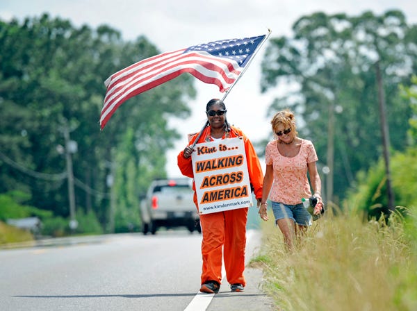 Kim Denmark, left, walks with Angie Battles of Steele on Wednesday along U.S. Highway 11 outside of Attalla. Denmark is undertaking a cross-country trek to raise awareness of homelessness.