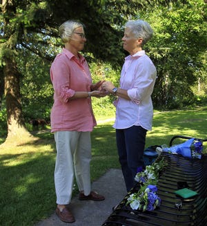Dorothy Dilliplane (right) slips on Alison Shiboski’s wedding band as the couple married Wednesday in Maurie Jacobs Park by the Willamette River. (Paul Carter/The Register-Guard)
