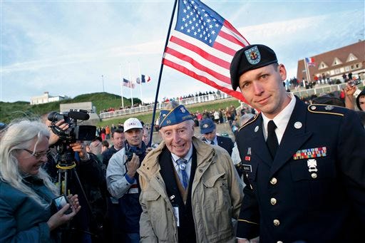 World War II veteran of the U.S. army 29th Infantry Division, Don McCarthy, 90, from Rhode Island, center, arrives for a D-Day commemoration, on Omaha Beach, western France, Friday June 6, 2014. Veterans and Normandy residents are paying tribute to the thousands who gave their lives in the D-Day invasion of Nazi-occupied France 70 years ago. World leaders and dignitaries including President Barack Obama and Queen Elizabeth II will gather to honor the more than 150,000 American, British, Canadian and other Allied D-Day troops who risked and gave their lives to defeat Adolf Hitler's Third Reich. (AP Photo/Thibault Camus)