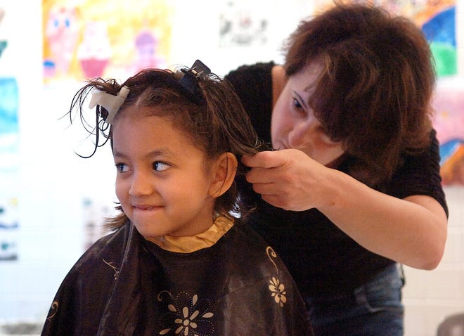 Rymas Aladmawy, 7, gets her hair cut from Leanne Soden during a Locks of Love fundraiser Saturday, May 31, at Salemwood School. Wicked Local Staff Photo / Nicole Goodhue Boyd