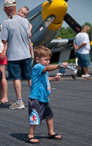 Ben Maynard of Randleman, 2.5 years old, flies his toy P-51 Mustang as the real thing sits quietly behind him 6.7.14. The P-51 was one of the big draws for the day. (PAUL CHURCH / THE COURIER-TRIBUNE)    
 A crowd gathers around the P-51 Mustang (yellow nose) after it parks at the NC Aviation Museum Fly-In 6.7.14. It was flown in by Alex Newsom of Cheraw SC. The P-51 was extremely popular with the attendees. (PAUL CHURCH / THE COURIER-TRIBUNE) 
 A Naval SNJ-5C lifts off for a fly over at the NC Aviation Museum's Fly-In 6.7.14. (PAUL CHURCH / THE COURIER-TRIBUNE)