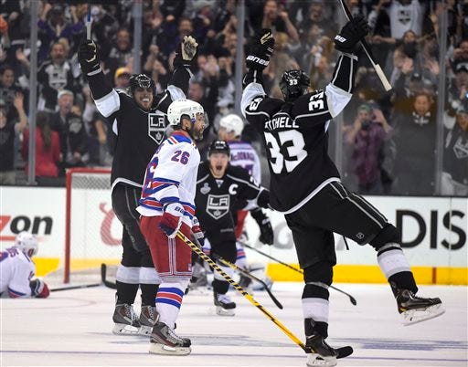 Los Angeles Kings right wing Dustin Brown, center, celebrates after scoring the game-winning goal, along with center Anze Kopitar, second from left, and defenseman Willie Mitchell, right, as New York Rangers center Brad Richards, left, lies on the ice and Martin St. Louis (26) watches during the second overtime period in Game 2.