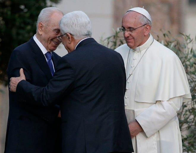 Pope Francis looks at Israel's President Shimon Peres, left, and Palestinian President Mahmoud Abbas greet each other during an evening of peace prayers in the Vatican gardens, Sunday, June 8, 2014. Pope Francis waded head-first into Mideast peace-making Sunday, welcoming the Israeli and Palestinian presidents to the Vatican for an evening of peace prayers just weeks after the last round of U.S.-sponsored negotiations collapsed. (AP Photo/Gregorio Borgia)