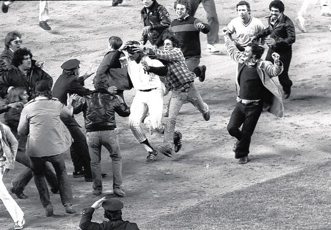 Even before he can circle the bases on his 9th inning, American league pennant-winning homer, New York Yankees Chris Chambliss is besieged by fans, at Yankee Stadim in New York, Oct. 14, 1976. (AP Photo)