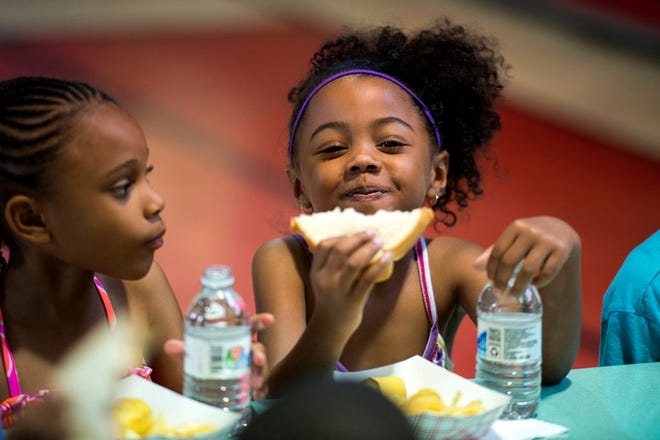 Camara Bennet, 5, is all smiles as she eats her sandwich as kids are served lunch during the Boys and Girls Club of Greater Peoria Summer 2014 program at the East Bluff Community Center Monday.
