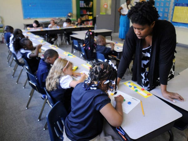 A Douglass Academy kindergarten teacher assistant works with students on a colors and numbers lesson at the school in Wilmington on Wednesday, August 28, 2013.