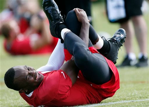 Atlanta Falcons receiver Julio Jones laughs with a teammate as he stretches during an NFL football practice in Flowery Branch, Ga., Tuesday, June 10, 2014. Jones, who missed most of last season with a foot injury, says he hasn't been cleared to practice but stretched during team's workout. (AP Photo/John Bazemore)