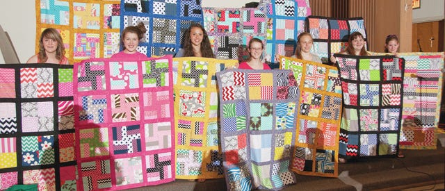 SEW BEAUTIFUL — Uwharrie Charter Academy students showing off their quilts are, from left, Kyndall Bowen, Darby Vereyken, Adele Brumley, Tess Perdue, Gracie Baxter, Megan Chunn and Sarah Hunsucker. Guild members hold up the others made by Deonna King, Ariel Umphenour, Katelyn Clewis, Sarah Moody and Amy Garcia. (Paul Church/The Courier-Tribune)