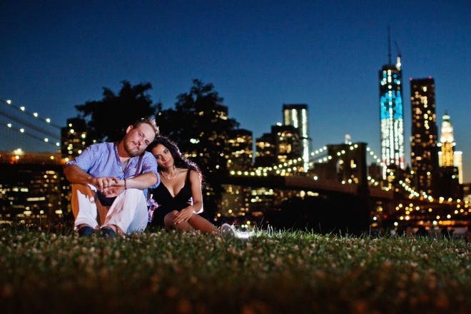 Kristain and Anzalee Rhodes  sit at Brooklyn Bridge Park in New York. The couple are hiring photographers from I Heart New York to document their experiences as young parents.
