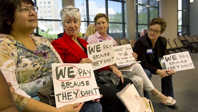 The Travis County Commissioners Court met Tuesday, June 10, 2014, to hear public testimony and consider whether to challenge the 2014 commercial property tax roll. Residential homeowners and activists argue they are footing the bill for higher tax values when commercial entities should be pulling their own weight. This group of women, including from L-R: Diane Counts; Brigid Shea, Democratic nominee for Travis County commissioner;, Laura Pressley, candidate for Austin City Council Place 4; and Tina Cannon, candidate for Austin City Council Place 10, hold protest signs as the court recessed into executive session to take up the issue.