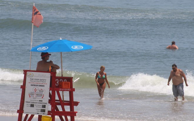 A lifeguard just north of the Daytona Beach Pier keeps an eye on ocean bathers Wednesday, June 11, 2014. Beach Safety Ocean Rescue lifeguards had a busy Sunday with 51 rescues and nearly doubled that number in the days that followed.