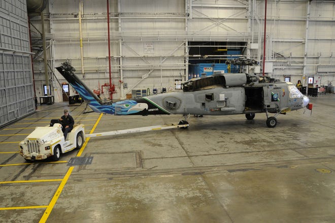 An aircraft worker from Fleet Readiness Center Southeast tows the Royal Australian Navy 725 Squadron's "Bromeo" aircraft into the bead blast hangar on March 25 to begin the refurbishment process.