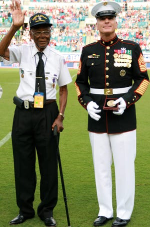 Former Army Pvt. 1st Class Samuel Muldrew, 91, stands with Marine Corps Sgt. Maj. Battaglia and waves to the crowd at the USA Men's Soccer World Cup Team soccer match against Nigeria in Jacksonville June 7.