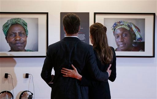 US actress Angelina Jolie, right, Special Envoy of the United Nations High Commissioner for Refugees, embraces her partner US actor Brad Pitt, left, as they view photographs of victims of violence at the 'End Sexual Violence in Conflict' summit in London, Thursday, June 12, 2014. The Summit welcomes governments from over 100 countries, over 900 experts, NGOs, Faith leaders, and representatives from international organizations across the world. (AP Photo/Lefteris Pitarakis, pool)
