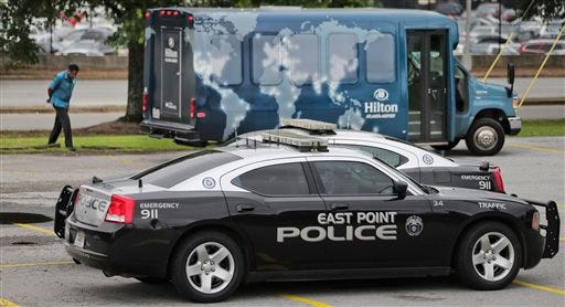 A driver walks outside his hotel shuttle bus, not involved in an accident, standing by, as East Point police complete their accident report inside their patrol cars near the scene of an accident, Thursday, June 12, 2014, in Fulton County, Ga. Authorities said several people were injured in a multi-vehicle wreck near Hartsfield-Jackson International Airport involving a hotel shuttle. (AP Photo/Atlanta Journal-Constitution, John Spink)