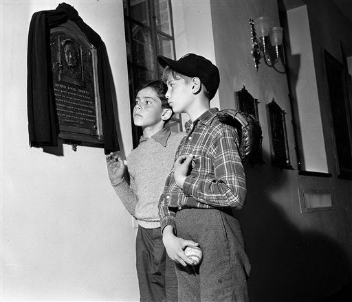 FILE - This June 5, 1941 file photo shows two boys stopping at a plaque for Lou Gehrig at baseball's Hall of Fame at Cooperstown, N.Y. A ceremony marking the 75th anniversary of the Hall of Fame will be held Thursday morning, June 12, 2014, on the front steps of the museum, with Hall of Famers Cal Ripken Jr. and Joe Morgan taking part.