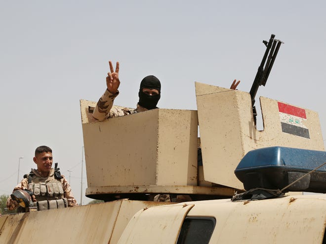 An Iraqi soldier flashes a V for victory sign while Iraqi men gather outside of the main army recruiting center to volunteer for military service Thursday in Baghdad, Iraq, after authorities urged Iraqis to help battle insurgents. The al-Qaida-inspired group that led the charge in capturing two key Sunni-dominated cities in Iraq this week vowed on Thursday to march on to Baghdad, raising fears about the Shiite-led government's ability to slow the assault following the insurgents' lightning gains.