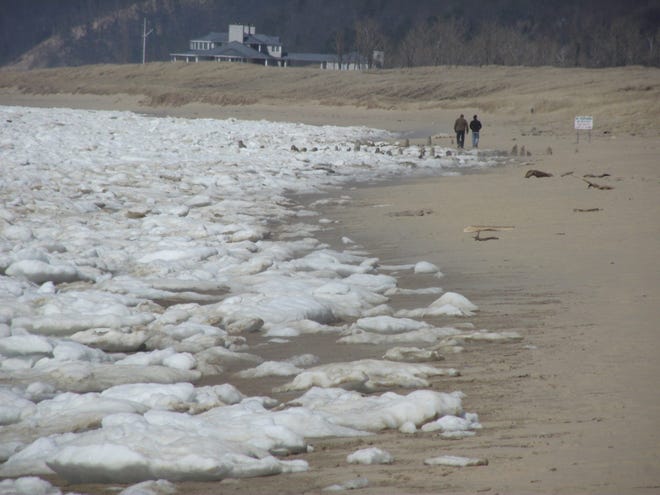 People walk along the beach in Saugatuck on April 18 as ice remains piled up on the Lake Michigan shore. Jim Hayden/Sentinel staff