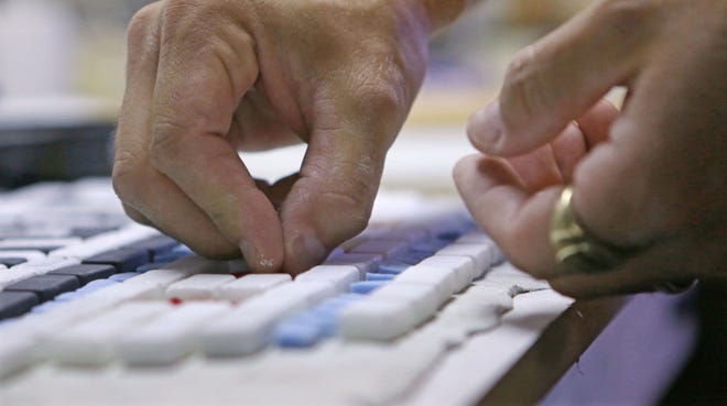 Chicago mosaic artist Jim Bachor works in his basement on Monday, June 9, 2014, placing tiles on his next mosaic art piece that reads “POTHOLES.” Bachor has filled a few potholes around the city and marks each one with a mosaic piece.