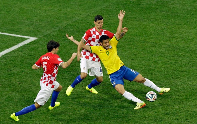 Brazil's Fred, right, falls after making contact with Croatia's Dejan Lovren during Thursday's World Cup-opening match at the Itaquerao Stadium in Sao Paulo, Brazil. The controversial play led to a successful Neymar penalty kick, which gave Brazil a 2-1 lead.