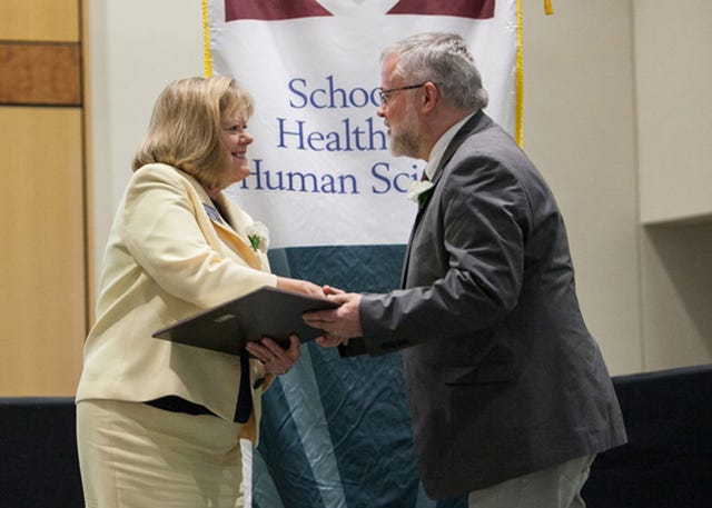 Celia R. Hooper, left, professor and dean of the University of North Carolina at Greensboro School of Health and Human Sciences, presents the 2014 HHS Pacesetter Award to Chuck Egerton, department chair for RCC’s Photographic Technology program. (RCC photo)