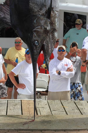 Ava D Captain Jerry Jackson, right, admires the 491.7-pound blue marlin brought to the weigh station Thursday at the Big Rock Blue Marlin Tournament. The big blue was big enough to claim third place in the week-long tournament, which runs through Saturday.