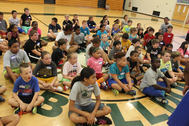 A seated group of Bulldog hoops campers listens intently for instructions.