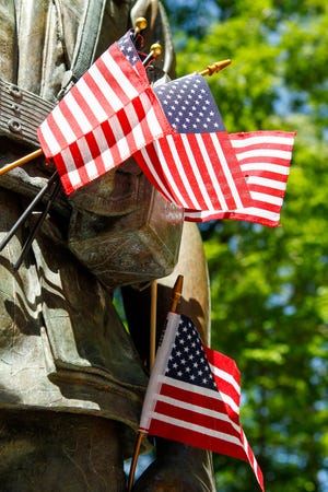Small flags are placed along the Bronze Marine Statue at the Beruit Memorial located at Lejeune Memorial Gardens.