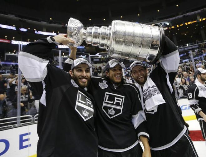 Los Angeles Kings' Dwight King, from left, Jordan Nolan and Jake Muzzin hoist the Stanley Cup after beating the New York Rangers in double overtime in Game 5 of the NHL Stanley Cup Final series, Friday, June 13, 2014, in Los Angeles.