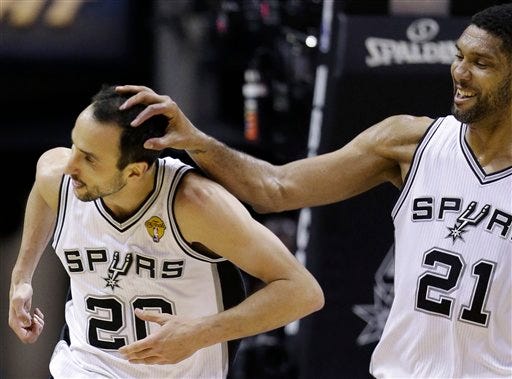 After dunking against the Miami Heat, San Antonio Spurs guard Manu Ginobili (20) is congratulated by forward Tim Duncan (21) during the first half in Game 5 of the NBA basketball finals on Sunday, June 15, 2014, in San Antonio. (AP Photo/David J. Phillip)