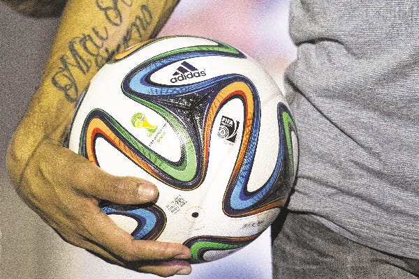 Brazilian midfielder Hernanes holds the official 2014 World Cup soccer ball after its unveiling late last year in Rio de Janeiro, Brazil. Competition among athletic companies – most notably, Adidas, Nike and Puma – is stiff as companies jockey for position in the soccer market.