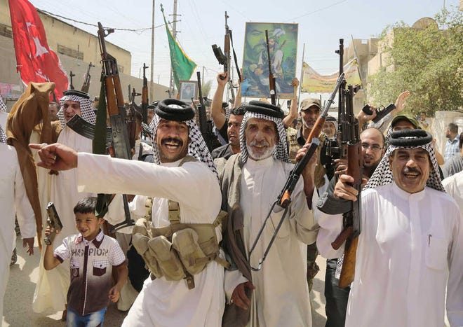Iraqi Shiite tribal fighters raise their weapons while chanting slogans against the al-Qaida inspired Islamic State of Iraq and the Levant (ISIL), in Baghdad's Sadr city, Saturday, June 14, 2014, after authorities urged Iraqis to help battle insurgents. Hundreds of young Iraqi men gripped by religious and nationalistic fervor streamed into volunteer centers across Baghdad Saturday, answering a call by the country's top Shiite cleric to join the fight against Sunni militants advancing in the north. The poster at top depicts Imam Hussein, a revered Shiite figure. (AP Photo/Karim Kadim)