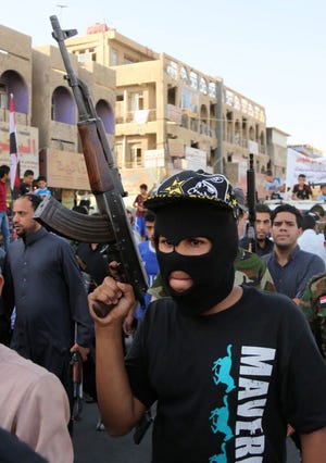 Shiite tribal fighters  raise their weapons and chant slogans against the al-Qaida-inspired Islamic State of Iraq and the Levant in the northwest Baghdad's Shula neighborhood in Iraq on Monday. Sunni militants captured a key northern Iraqi town along the highway to Syria early on Monday, compounding the woes of Iraq's Shiite-led government.