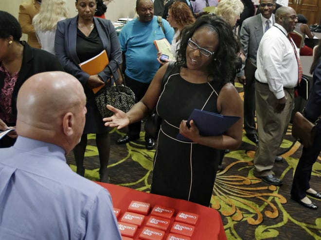 In this Thursday, June 12, 2014 photo, Marsha Lawson talks with a representative from CVS at the Cleveland Career Fair in Independence, Ohio. Optimism among chief executives of large U.S. companies has reached a two-year high, driven by greater optimism about hiring and sales. THE ASSOCIATED PRESS