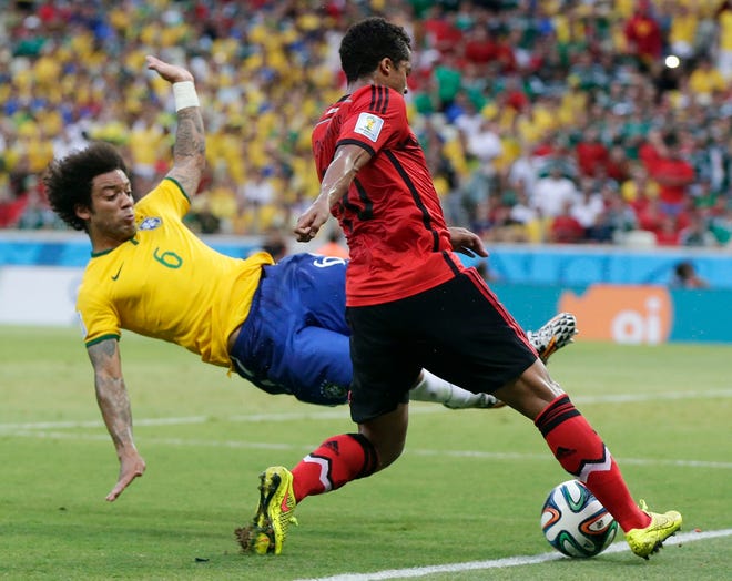 Brazil's Marcelo, left, dives to kick the ball away from Mexico's Giovani dos Santos during the group A World Cup soccer match between Brazil and Mexico at the Arena Castelao in Fortaleza, Brazil, Tuesday, June 17, 2014. THE ASSOCIATED PRESS