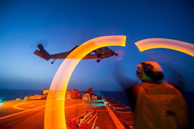 Boatswain's Mate Seaman Clayton Jackson, from Minneapolis, guides an MH-60S Seahawk helicopter assigned to the "Dragon Whales" of Sea Combat Squadron (HSC) 28 during a night time vertical replenishment aboard the guided-missile cruiser USS Philippine Sea (CG 58). Philippine Sea is deployed as part of the George H.W. Bush Carrier Strike Group supporting maritime security operations and theater security cooperation efforts in the U.S. 5th Fleet area of responsibility.