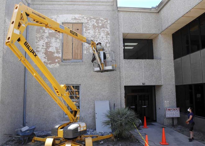 Clay Davis (left), with Esther Simpson serving as a safety lookout, chisels an outer layer of stucco off the historic McIntosh County Courthouse to restore some of the original exterior.
