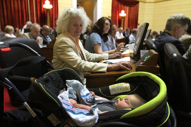 Rep. Edith Ajello, takes a look at 18- week-old Charles Kenneth Weber, son of Rep. Maria Cimini, center, in the blue shirt, late Thursday afternoon during the House session