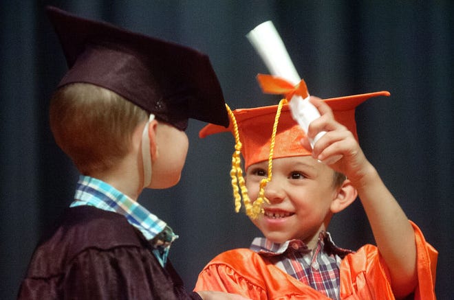 Joseph Guadalupe (right) finds a use for his diploma Friday afternoon after graduating from Pennsbury's Pre-K Counts program at Walt Disney Elementary School in Tullytown. Classmate Mason Wiser didn't seem to mind his cap being knocked down since he too earned a diploma.