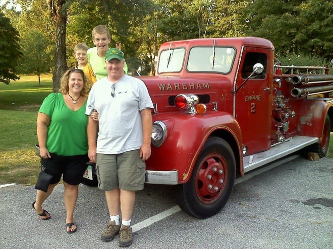 Howard T. Smith with his fiancée Amy and two sons, Cam and Aidan, in front of his vintage 1946 Maxim pumper.