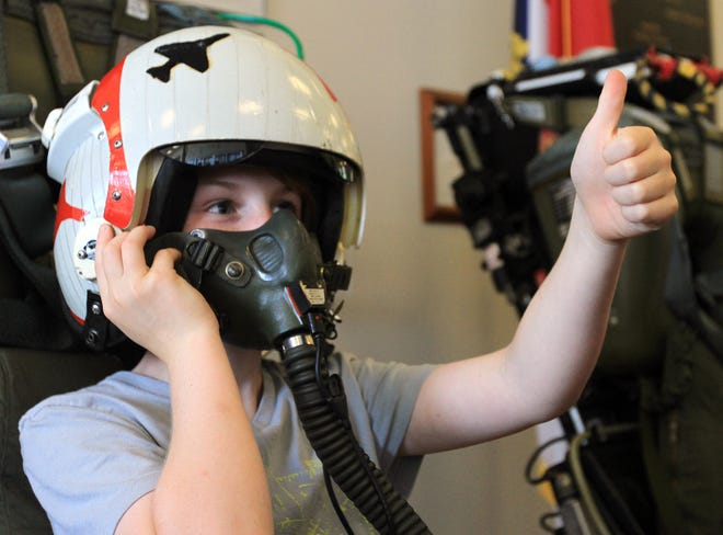 Levi Walter, 9, of Newport, gives a thumb’s up as he wears a helmet and air mask while sitting in an ejection seat during the Eastern Carolina Aviation Heritage Foundation Fly-In on Friday at the Havelock Tourist and Event Center. ‘It was cool,’ he said of wearing the helmet and mask.
