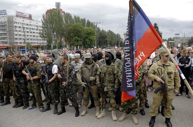 Pro-Russian fighters gather to take an oath in Donetsk, eastern Ukraine Saturday, June 21, 2014. Ukrainian President Petro Poroshenko ordered his forces to cease fire Friday and halt military operations for a week, the first step in a peace plan he hopes will end the fighting that has killed hundreds. The Kremlin dismissed the plan, saying it sounded like an ultimatum and lacked any firm offer to open talks with insurgents. Separatist leaders have also rejected the ceasefire and said they will not disarm. In Donetsk, a group of armed men gathered in the central square to take a military oath to the self-proclaimed Donetsk People’s Republic.(AP Photo/Dmitry Lovetsky)