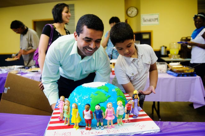 Nadeem Ramiydh and his son Abdulazeez Ramiydh, 8, bring out a World Refugee Day decorated cake during a local celebration Saturday at Broadway Christian Church. Hundreds of refugees have settled in Columbia over the past decade.
