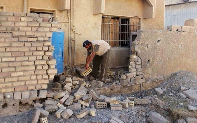 Abu Rasool al-Kubaisi clears debris at his home after a bombing in Fallujah, 40 miles west of Baghdad, Iraq, Sunday, June 22, 2014. Sunni militants have seized another town in Iraq's western Anbar province, the fourth to fall in two days, officials said Sunday, in what is shaping up to be a major offensive in one of Iraq's most restive regions. THE ASSOCIATED PRESS
