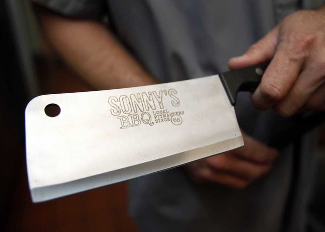 DARON.DEAN@STAUGUSTINE.COM Richard Irvin holds a meat cleaver that was presented to him Upon completing the Sonny's BBQ Pitmaster program.