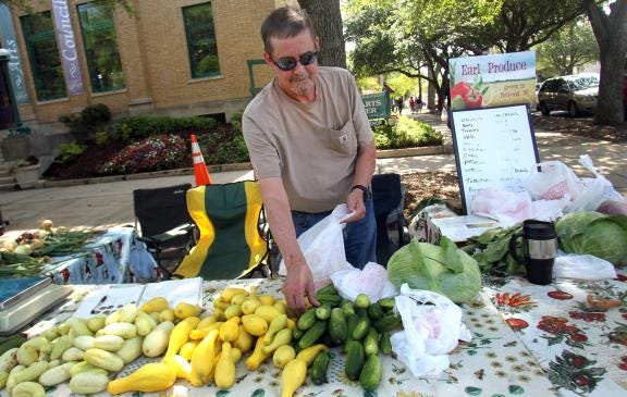 David Burton helps sell produce from Jim Earl's farm at Shelby Farmers Market.